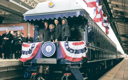 Barack y Michelle Obama, junto a la pareja vicepresidencial Joe y Jill Biden, saludan desde la parte trasera del tren, a la multitud que los vitoreaba durante el recorrido hacia Washington.